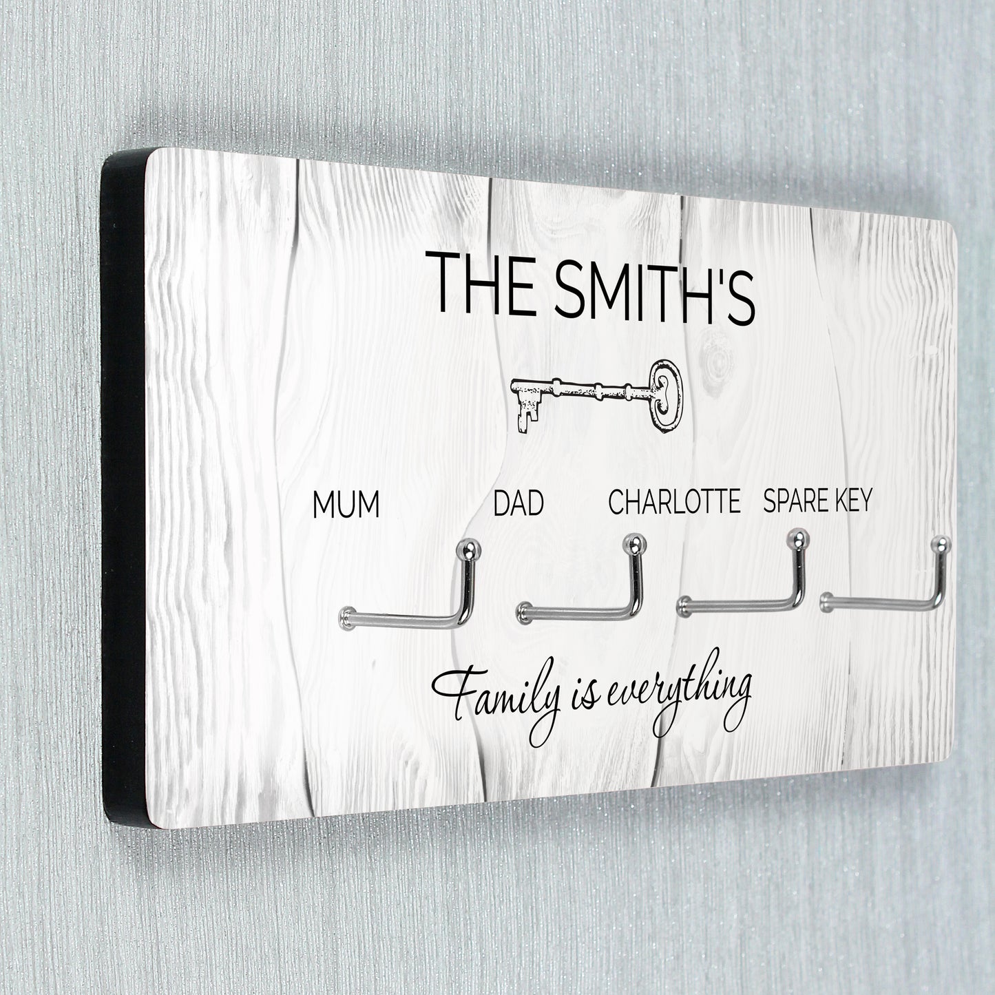 Key holder with hooks for keys, personalised with 'The Smiths' and 'Family is everything' text on a wooden pattern background.