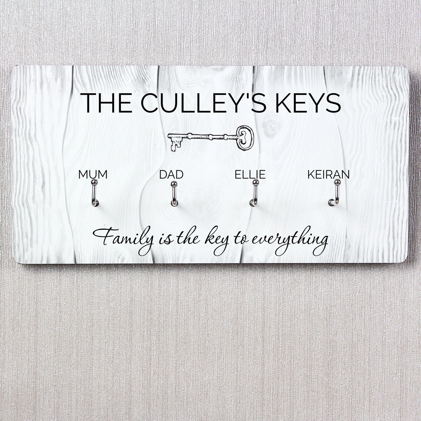 Key holder with keys for 'Mum', 'Dad', 'Ellie', and 'Keiran' on a wooden background.