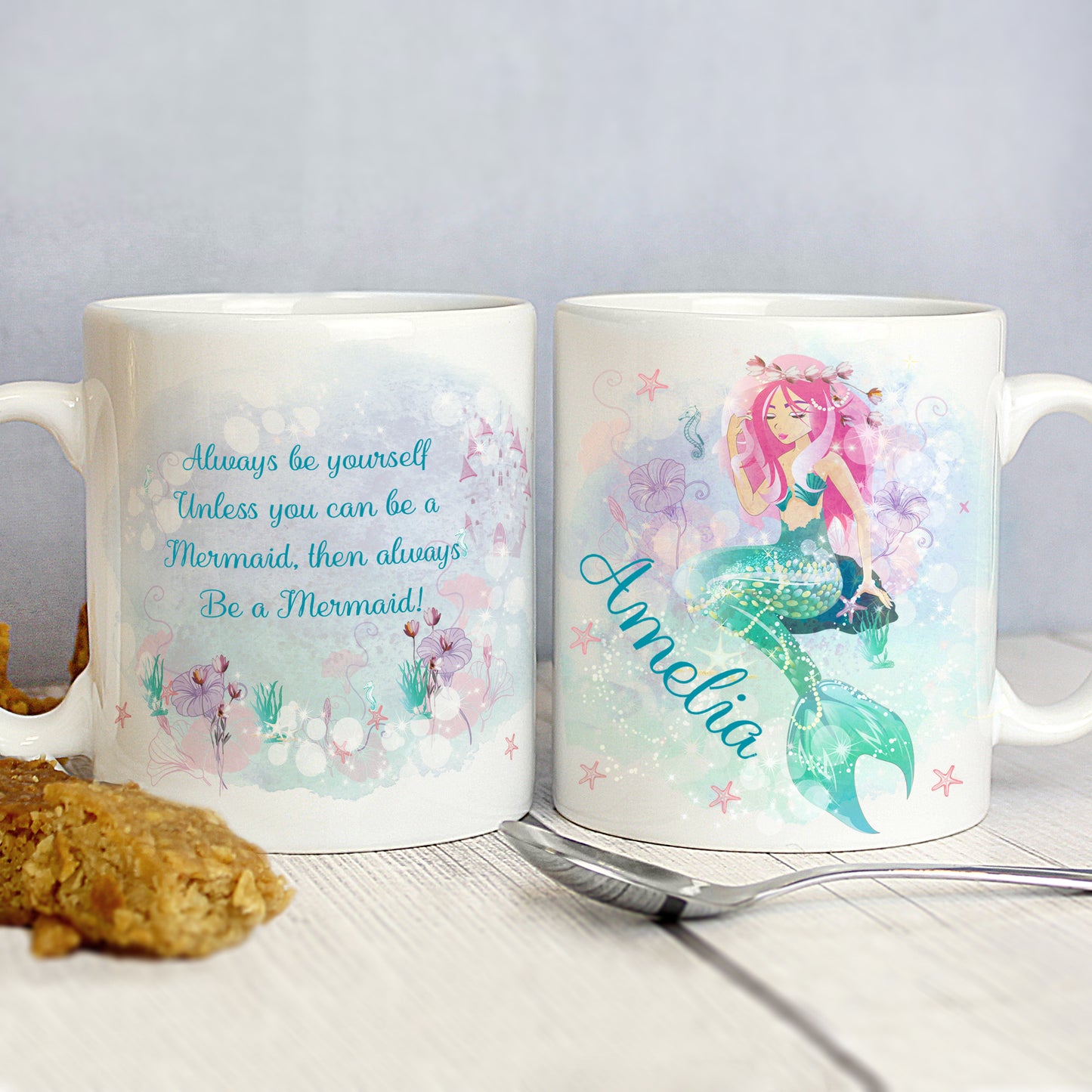Two mugs with mermaid designs and text on a light gray background