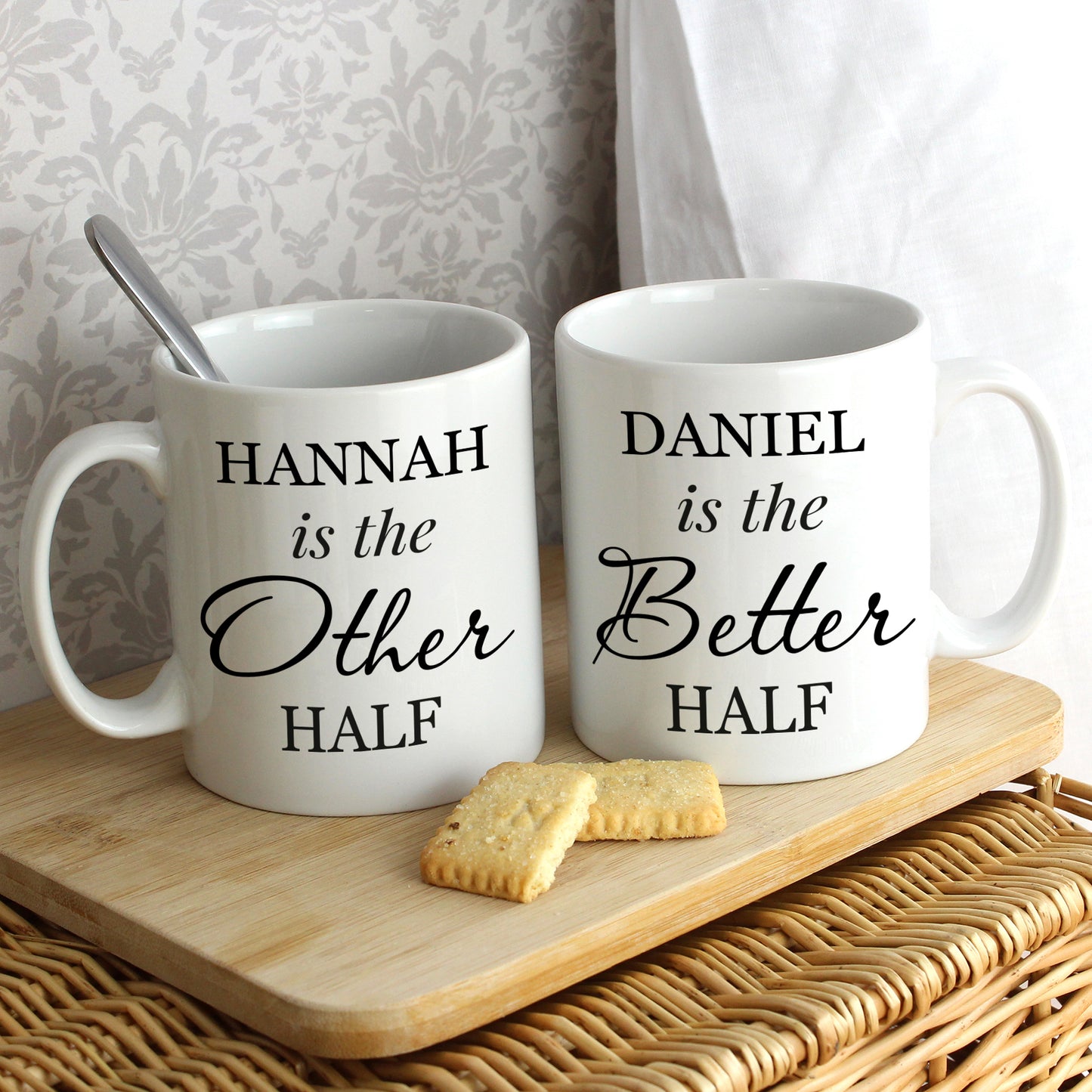Two white mugs with personalised text on a wooden tray with cookies.