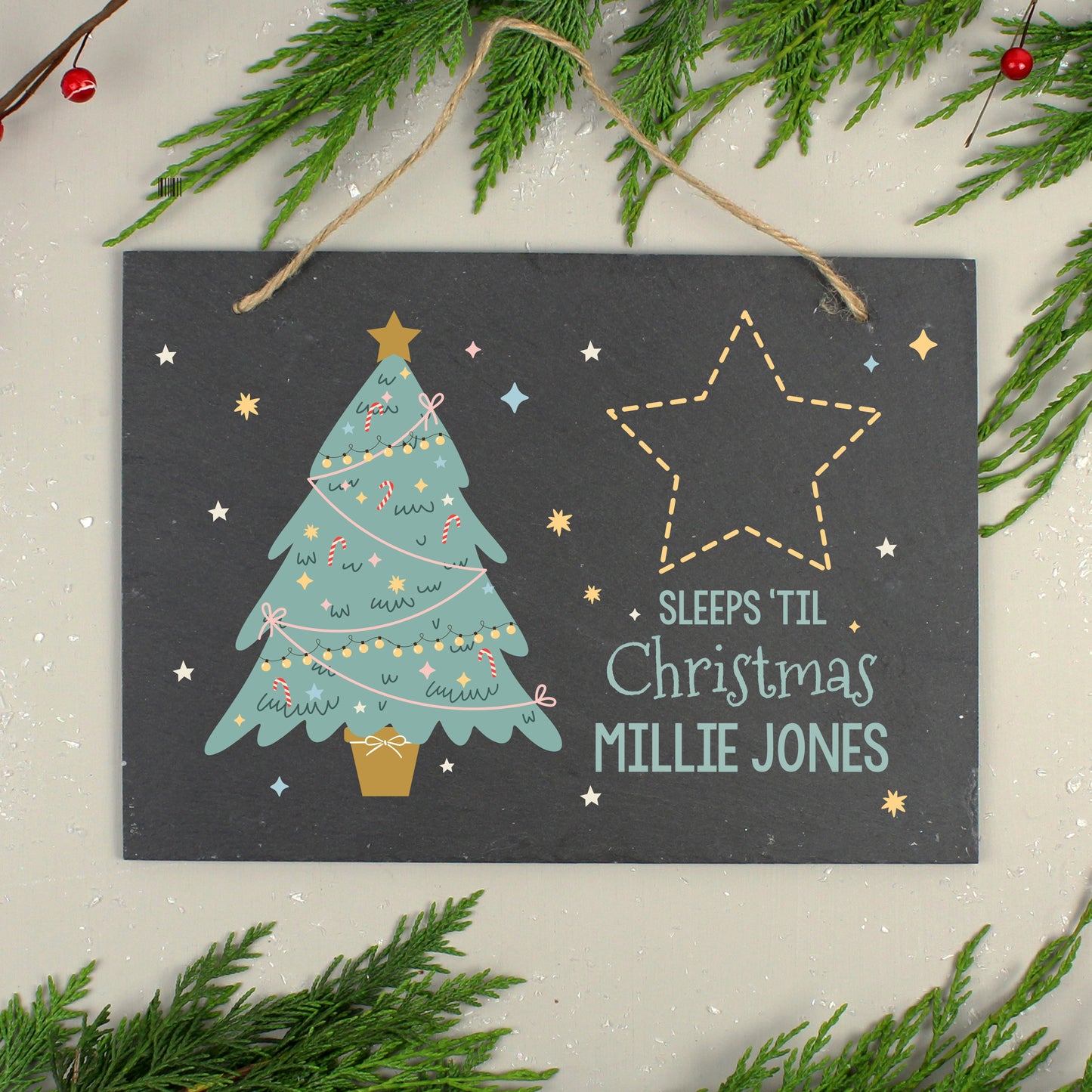 Decorative Christmas sign with a tree and star design, surrounded by greenery on a light background.