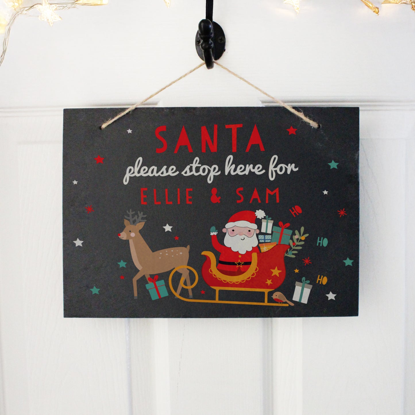 Christmas-themed sign with Santa, reindeer, and text 'Santa please stop here for Ellie & Sam' on a black background.