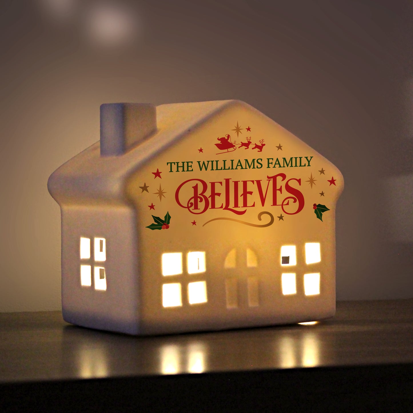 Decorative house-shaped light with 'The Williams Family Believes' text on a dark background