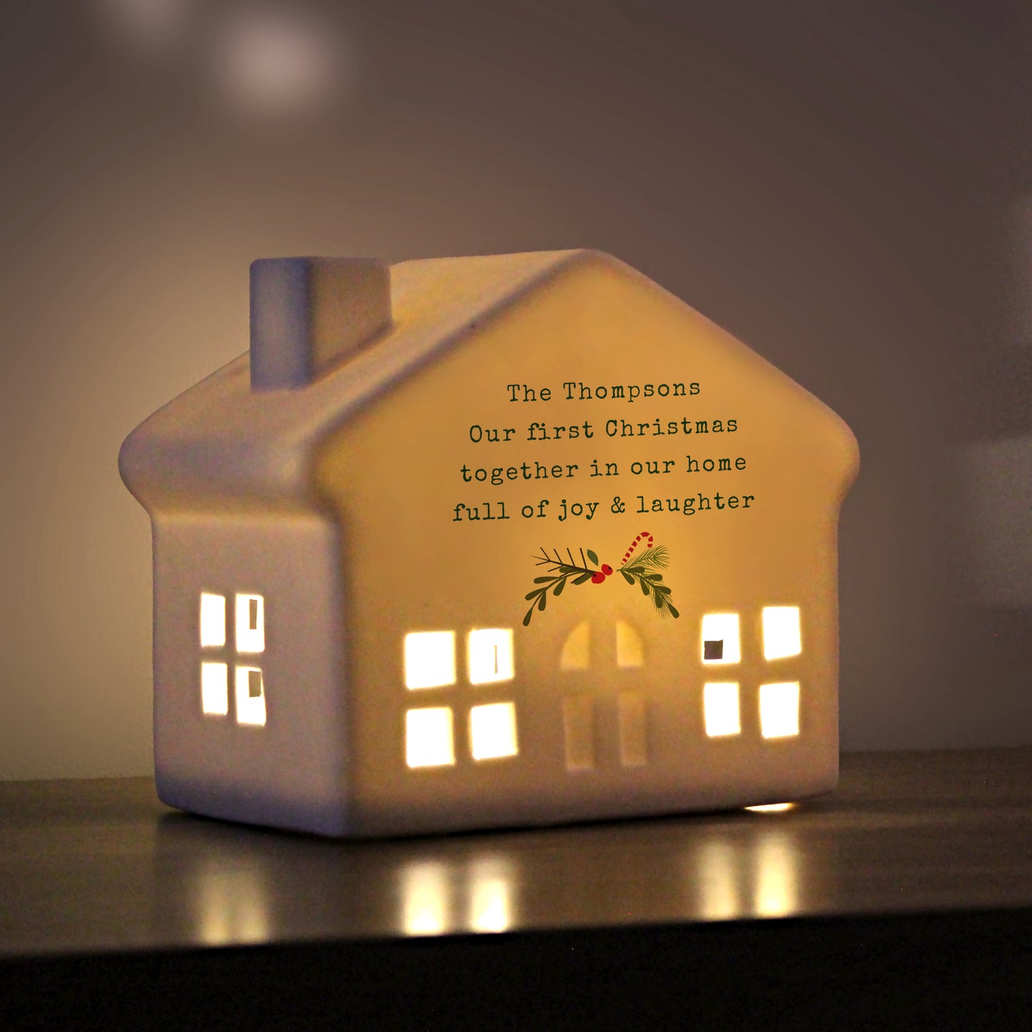 Ceramic house-shaped light with personalized message on a dark background