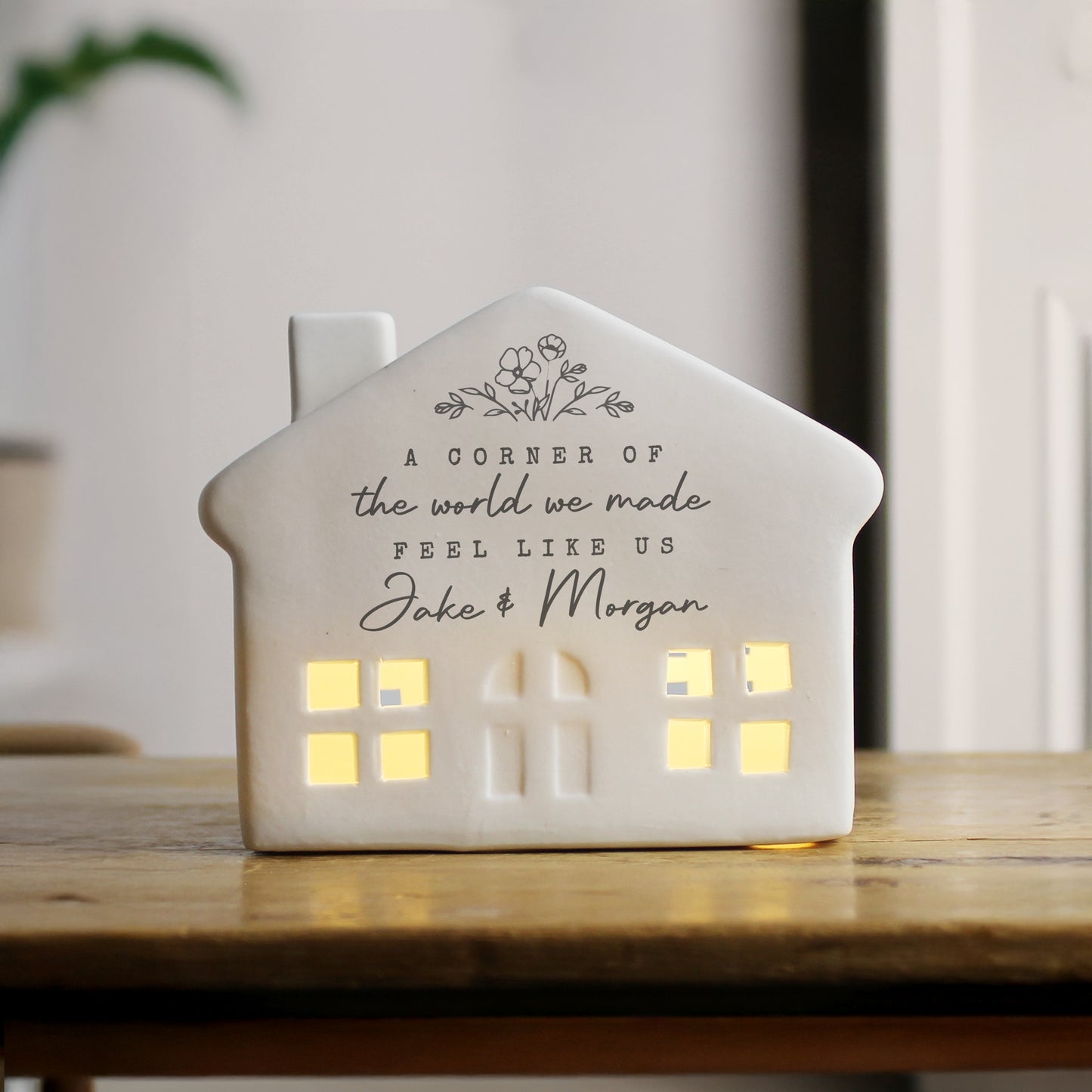 Ceramic house-shaped lantern with personalised text on a wooden surface