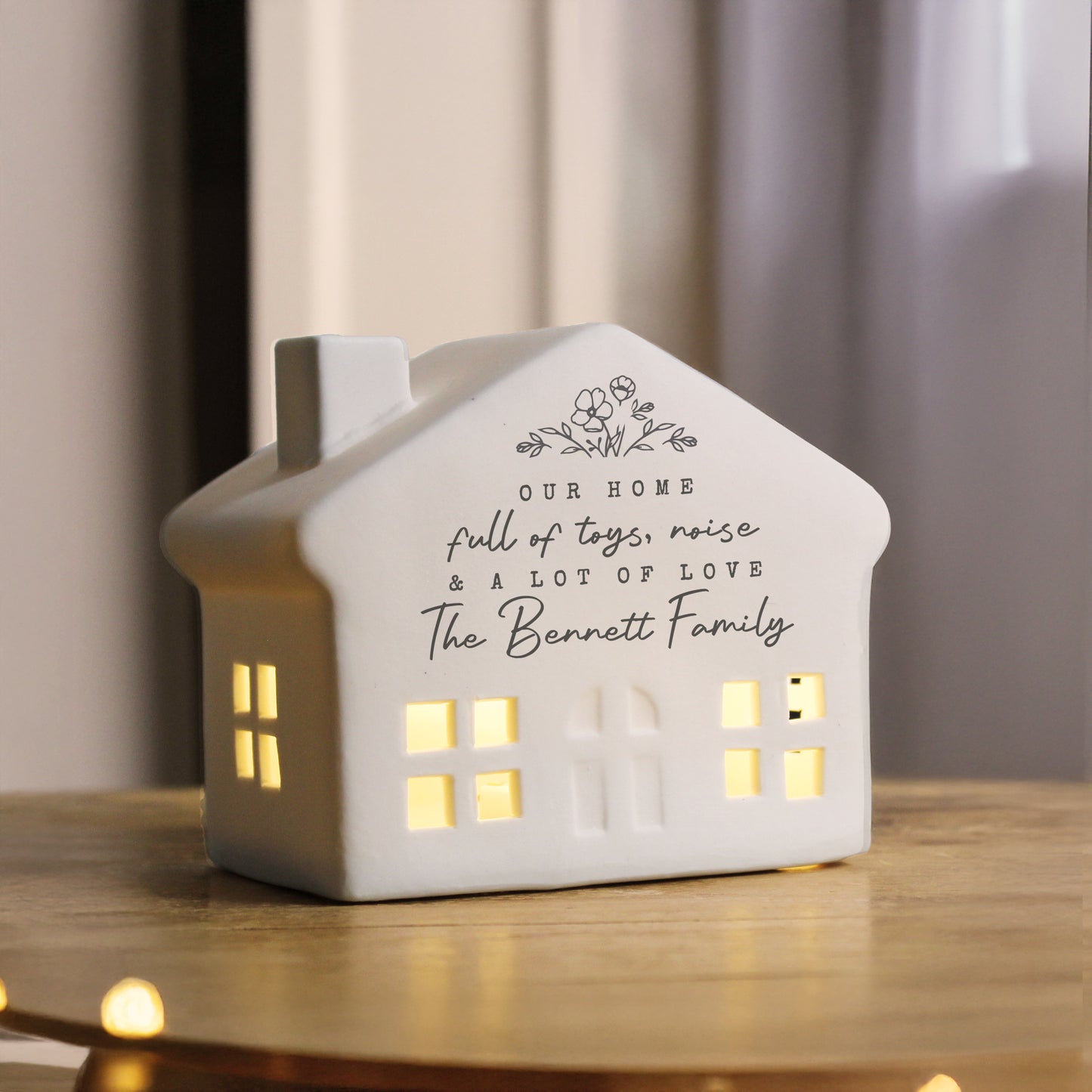 House-shaped decorative light with personalised text on a wooden surface