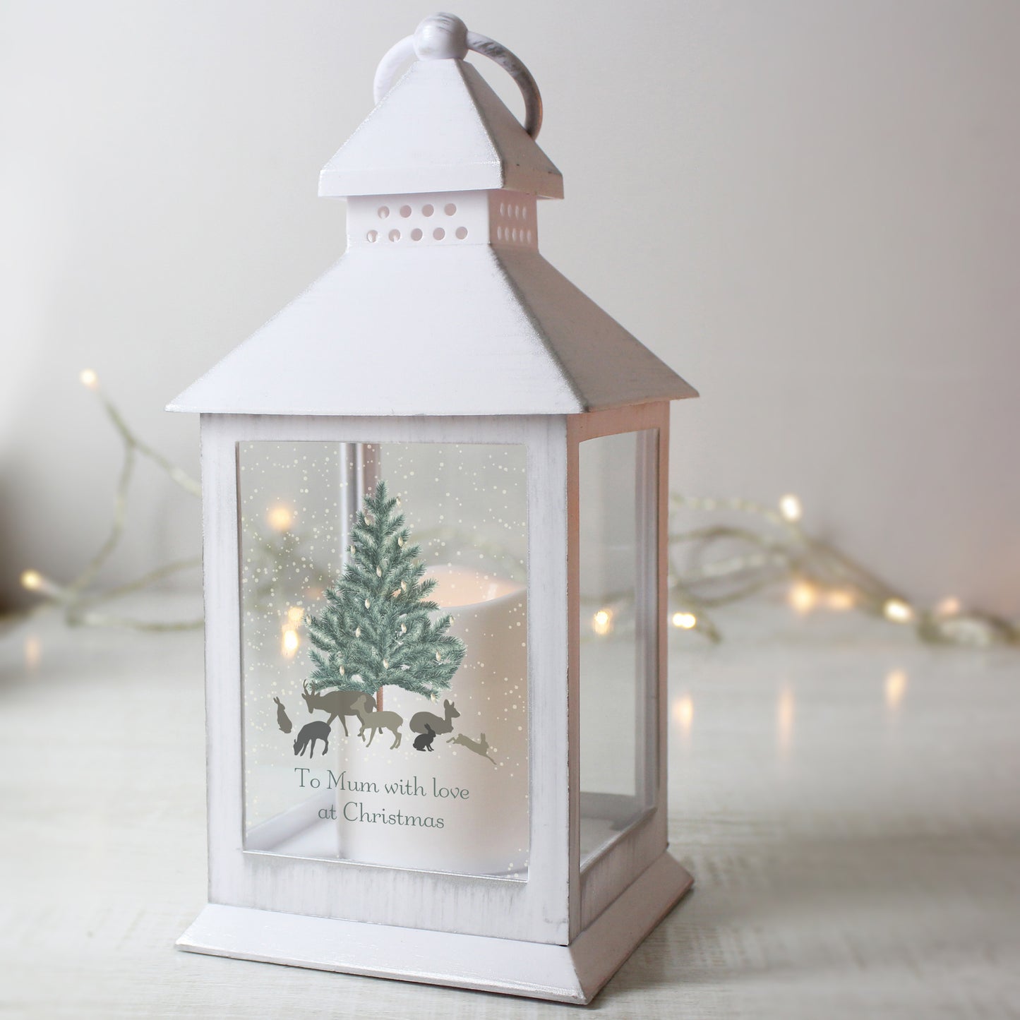 White lantern with Christmas design and tree inside, on a light background