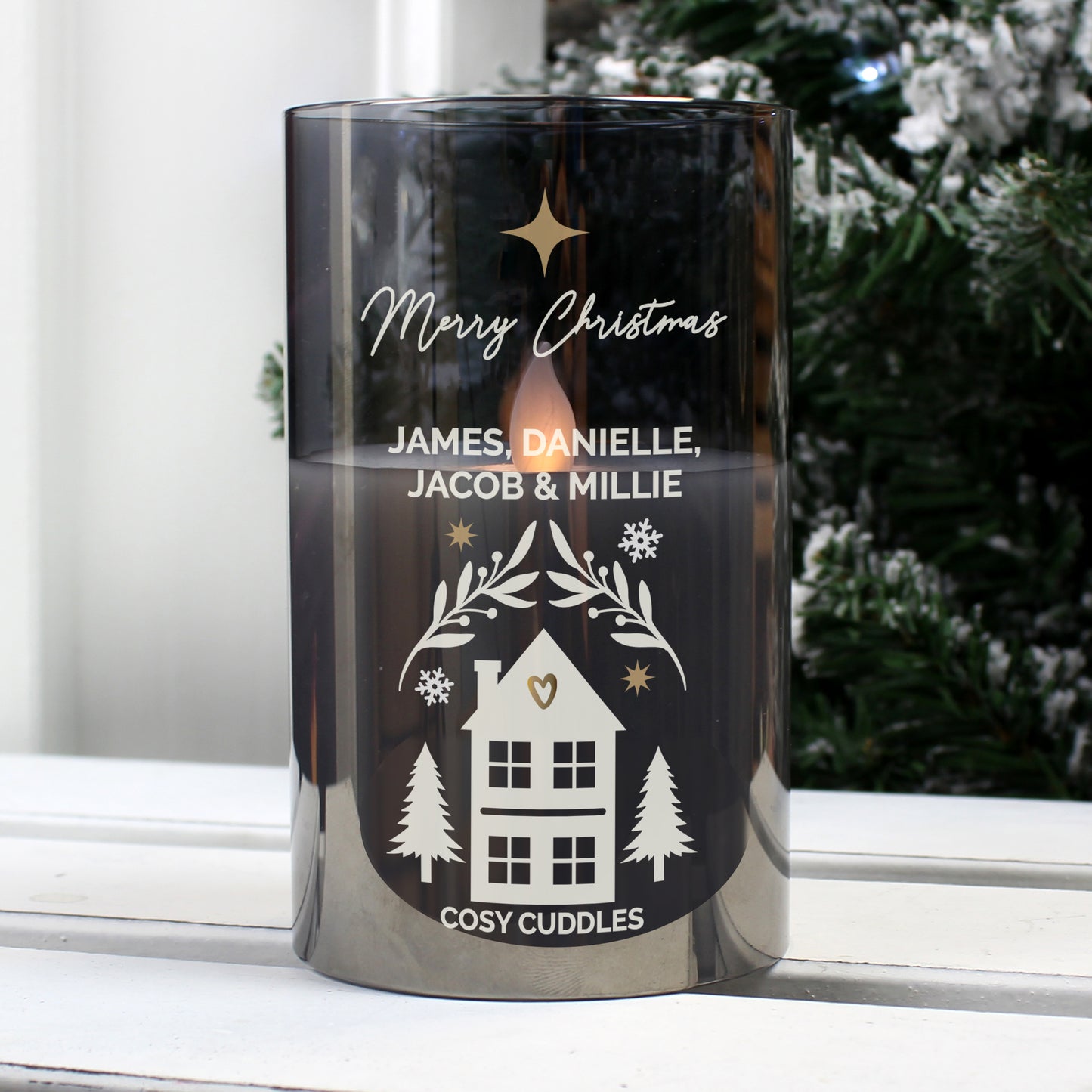 Decorative candle with personalised text on a windowsill with a snowy outdoor background