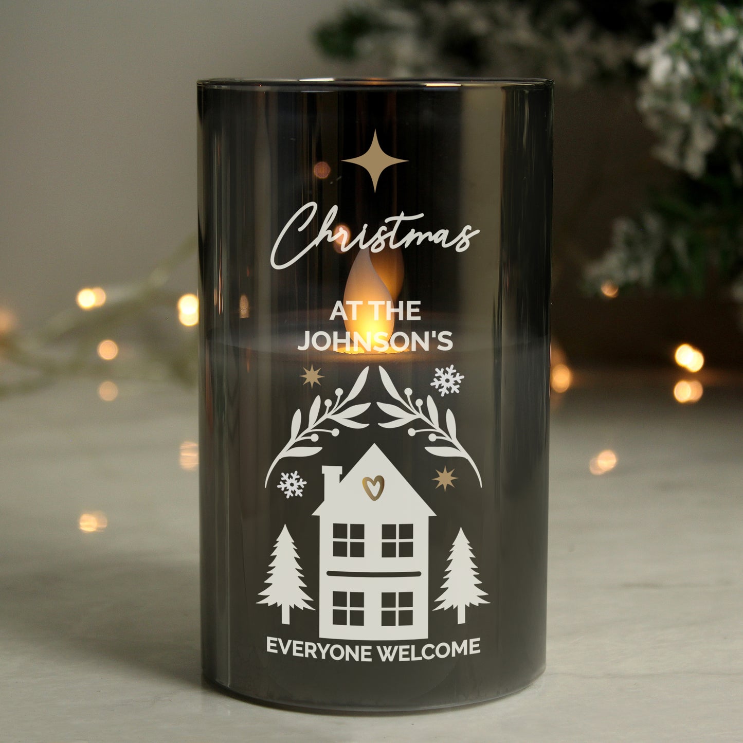 Black candle holder with Christmas design and personalized text, glowing softly.