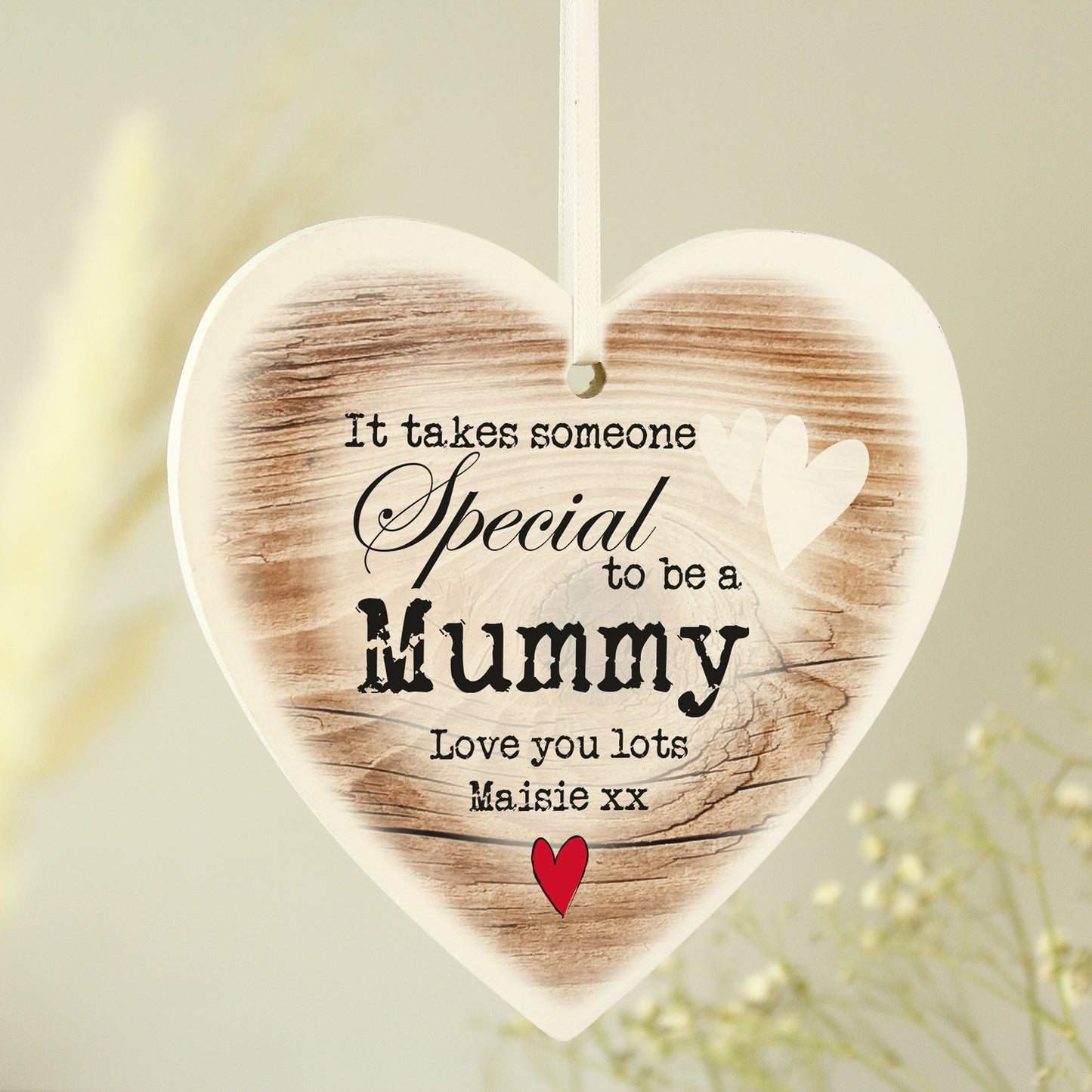Heart-shaped wooden plaque with printed text and a red heart on a light background