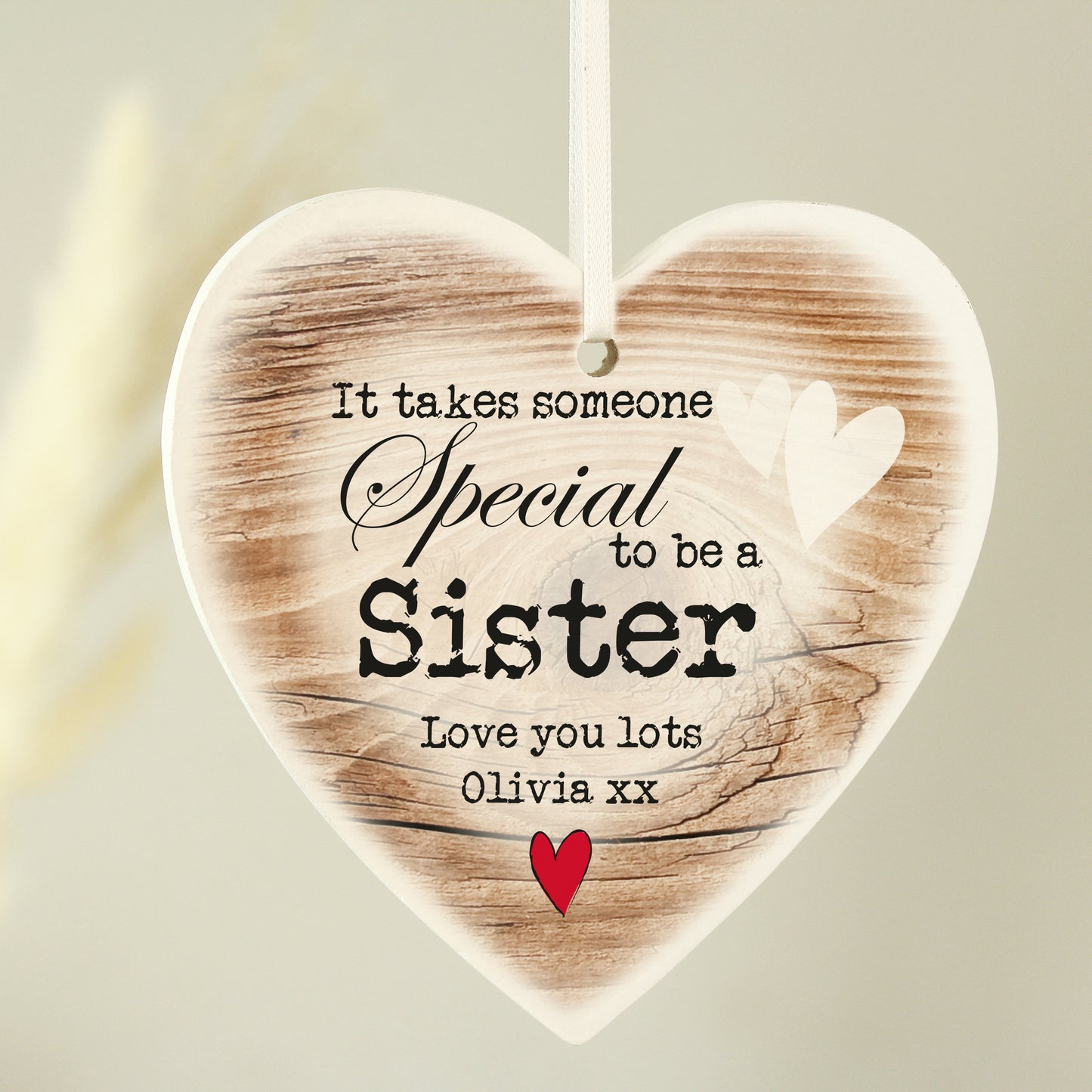 Heart-shaped wooden plaque with printed text and a red heart on a light background