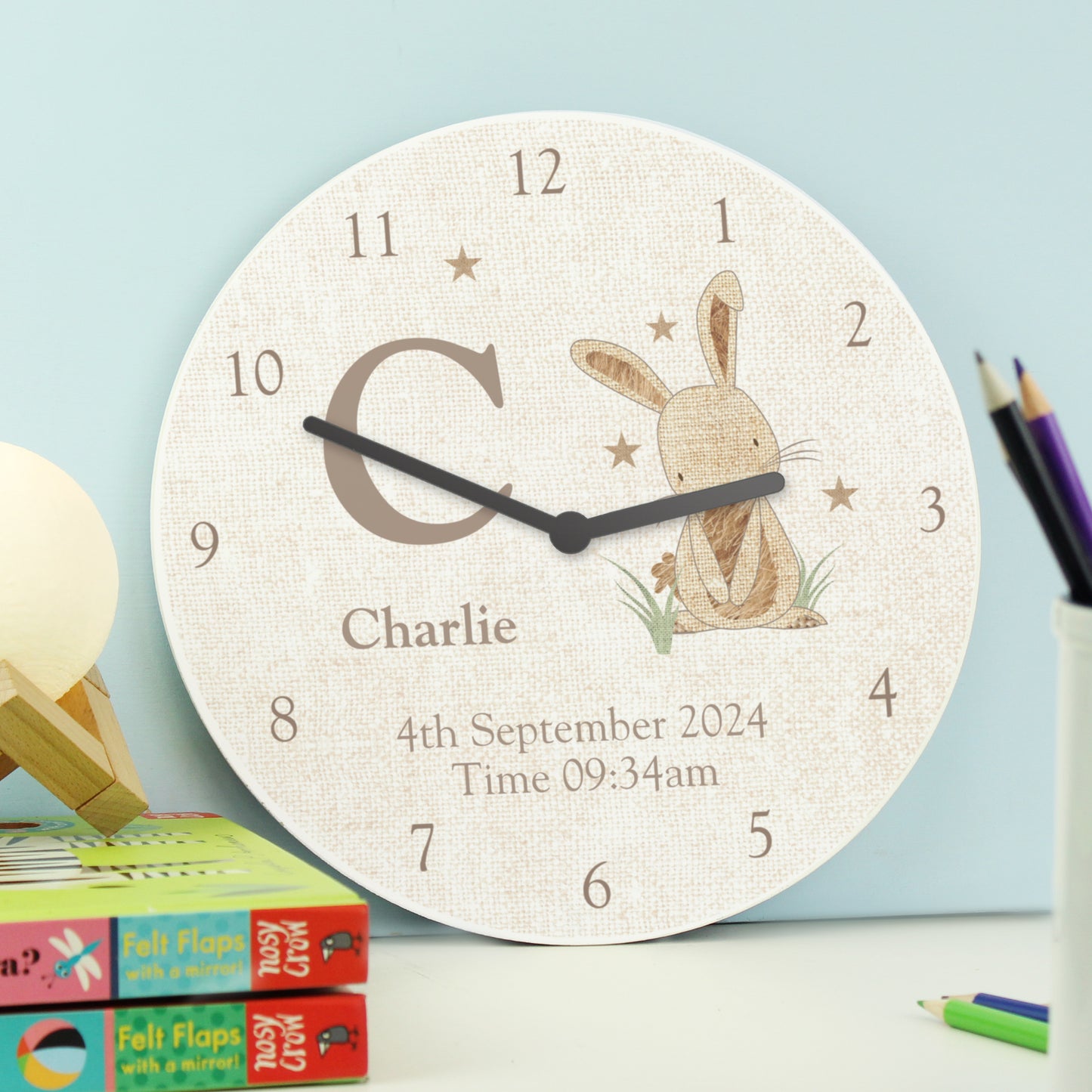 Children's wall clock with a rabbit design and personalised details on a light blue background.