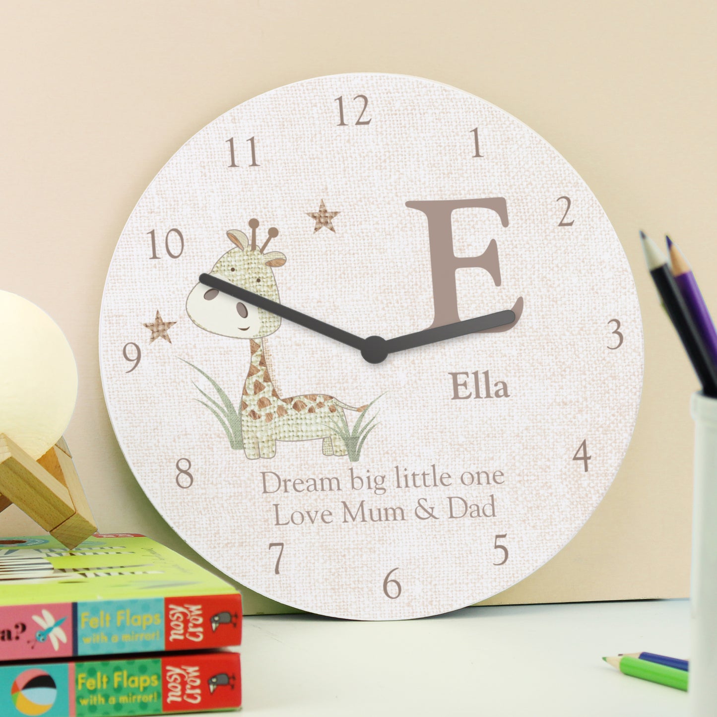 Children's wall clock with a giraffe design and personalised text on a desk.