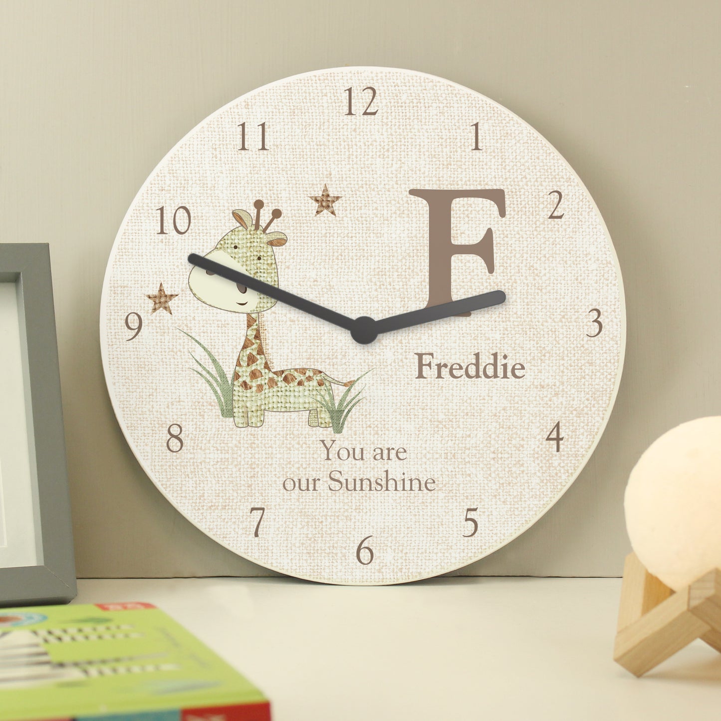 Children's wall clock with a giraffe design and personalised text on a neutral background