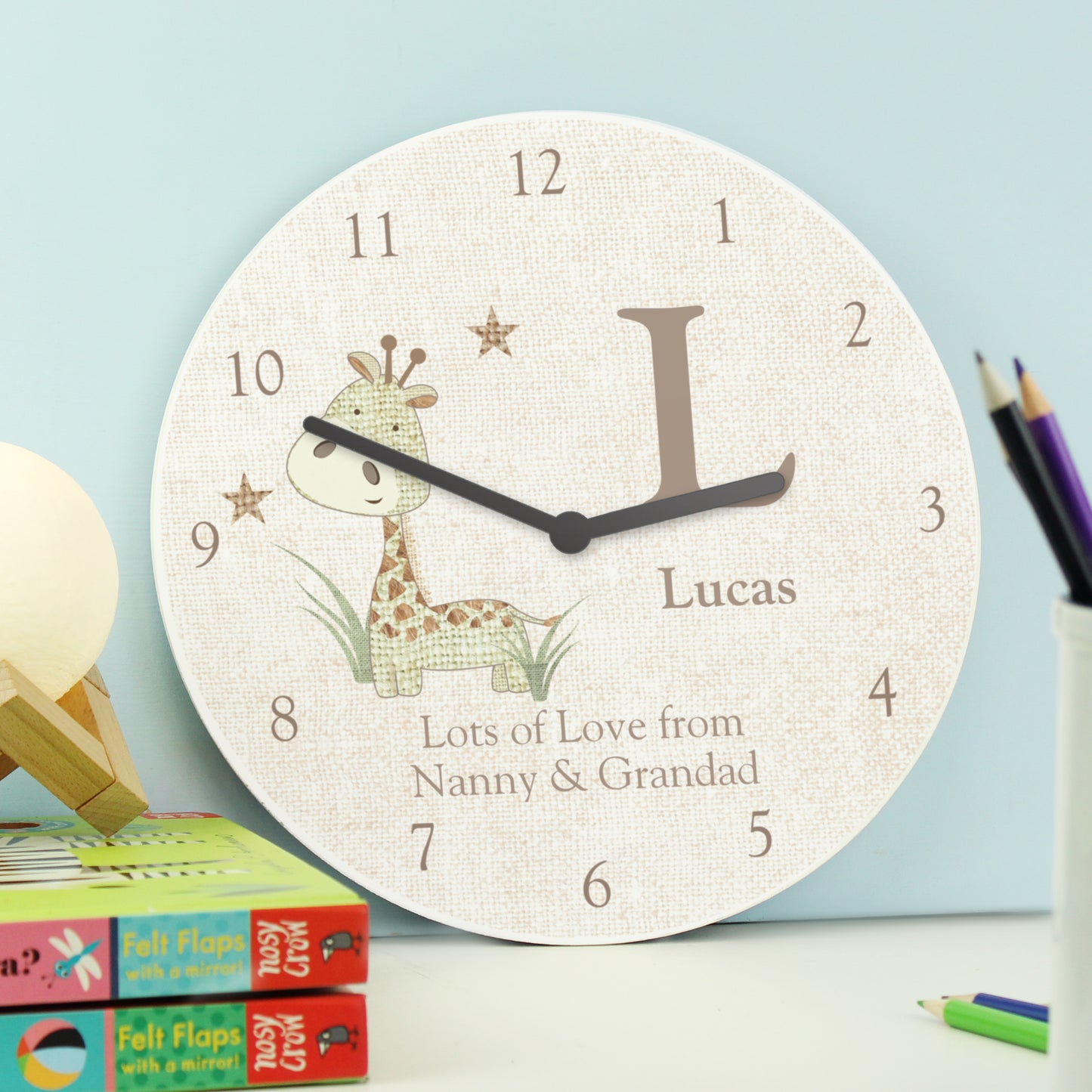 Children's wall clock with a giraffe design and personalised text on a light blue background.