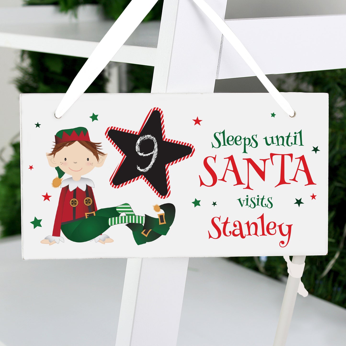Christmas countdown sign with elf and star design on a white stand.