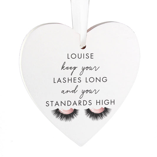Heart-shaped hanging decoration with eyelashes and text on a white background