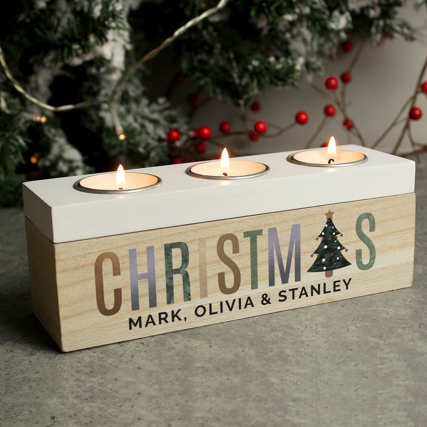 Wooden Christmas candle holder with three tealights, personalised with names, against a festive background.