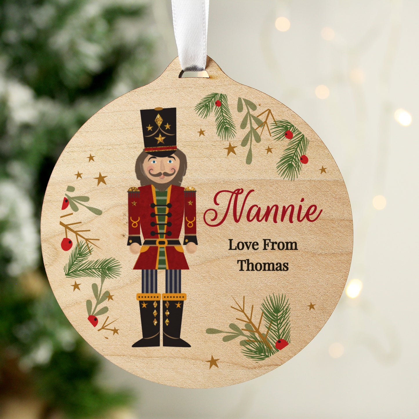 Personalised wooden nutcracker Christmas ornament for Nannie, custom tree decoration with festive foliage and ribbon, gift from Thomas.