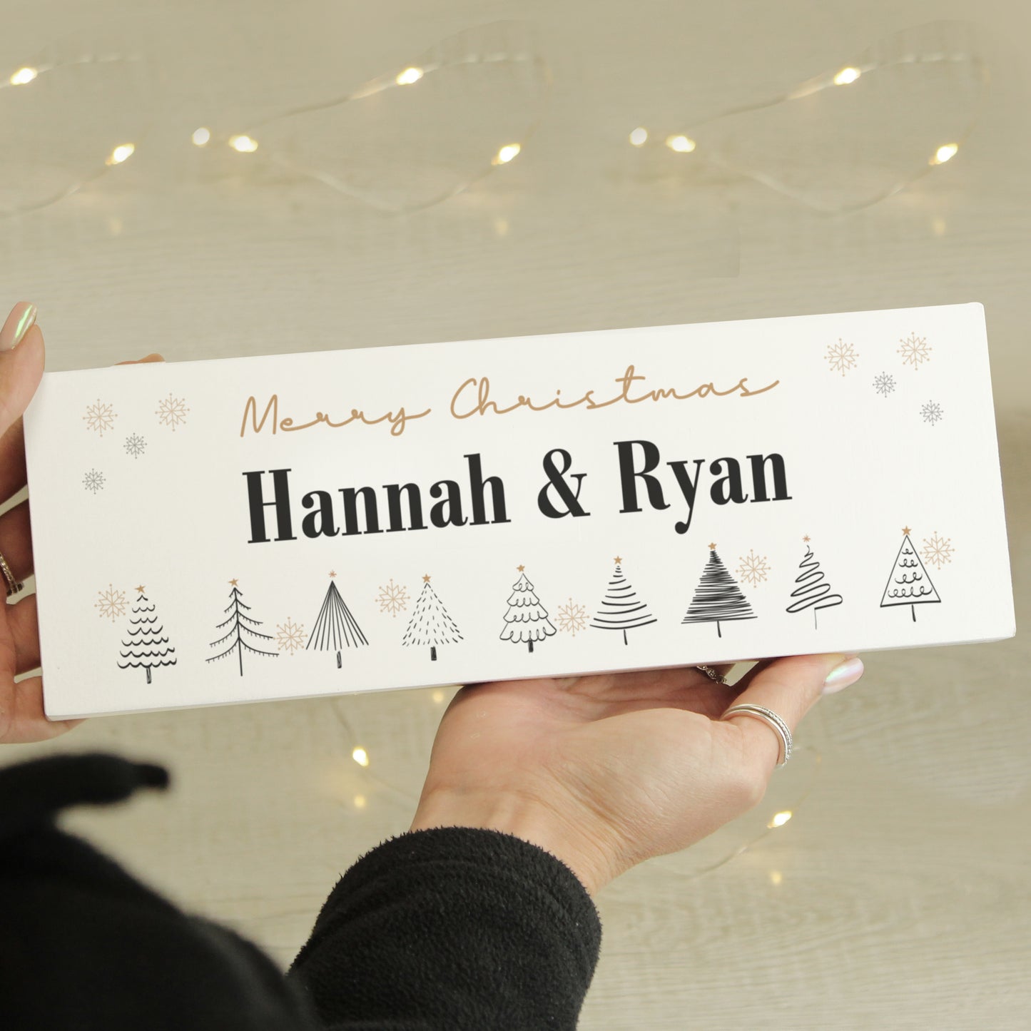 Hand holding a personalised Christmas card with 'Merry Christmas Hannah & Ryan' text and tree designs.
