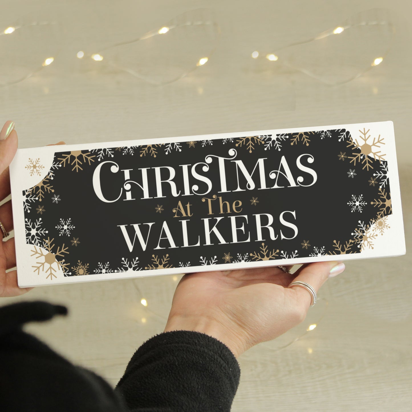 Personalised Christmas sign with 'Christmas at The Walkers' text held by a person.