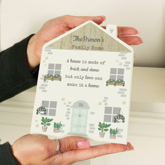 Personalised decorative wooden house sign featuring a light brick design, potted plants, and window flower boxes. Includes example text and a house number to showcase customisation for family homes.