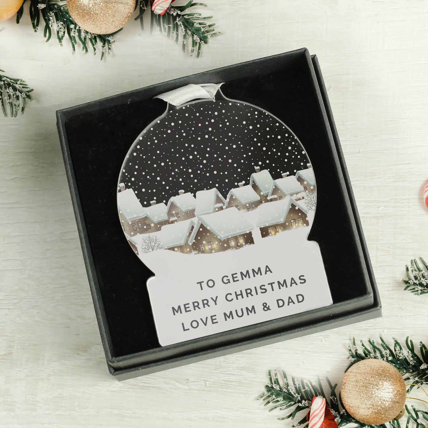 Personalized Christmas ornament in a box with festive decorations around