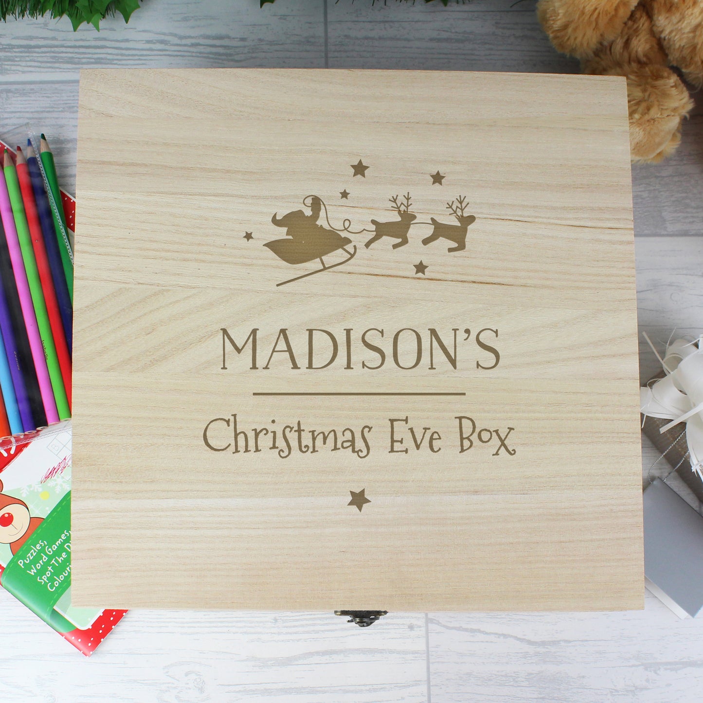Wooden Christmas Eve box with engraved text and design on a light wooden surface.
