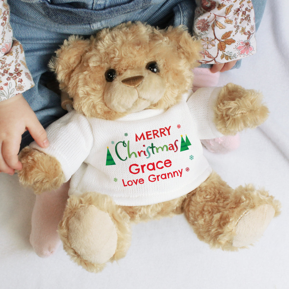 Teddy bear wearing a Christmas-themed shirt with personalised text, held by a child.