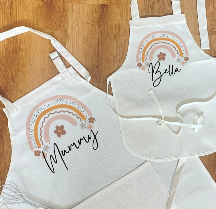 Unique personalised matching aprons for mummy and child featuring custom names and pastel rainbow design – perfect gift for baking together or Mother's Day.