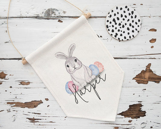 Unique personalised Easter wall flag featuring a cute grey bunny illustration with pastel Easter eggs and custom name “Harper” – a charming gift for children or festive seasonal decor.