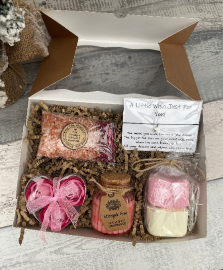 Gift set with soap, candle, and bath bomb in a box on a wooden surface
