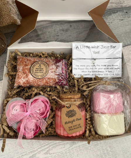 Gift set with bath bombs, candle, and soap in a box on a wooden surface