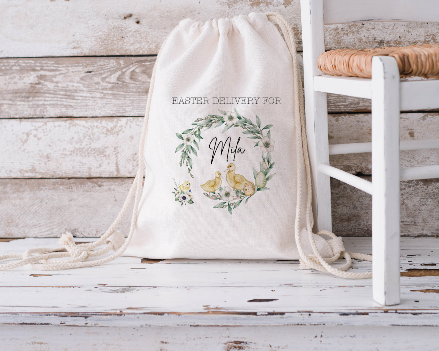 Personalised Easter drawstring bag featuring yellow chicks and floral wreath with custom name "Mila" on natural cotton fabric. Ideal for Easter egg hunts, spring gifts, or seasonal storage. Eco-friendly reusable Easter sack for kids.