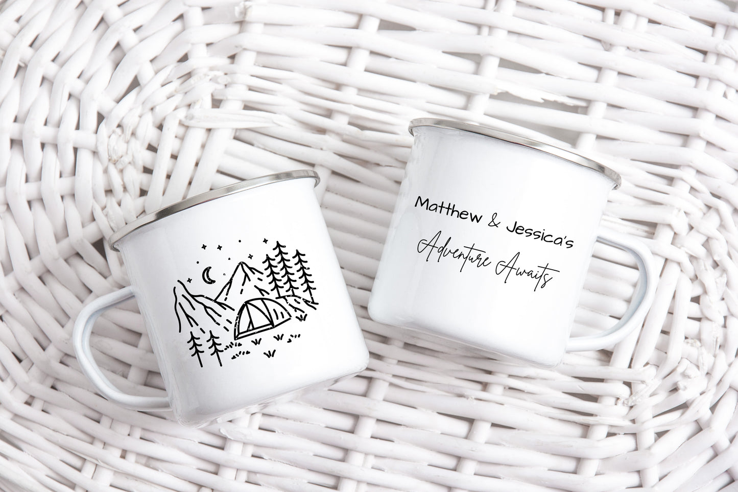 Two white mugs with black camping design on a wicker surface