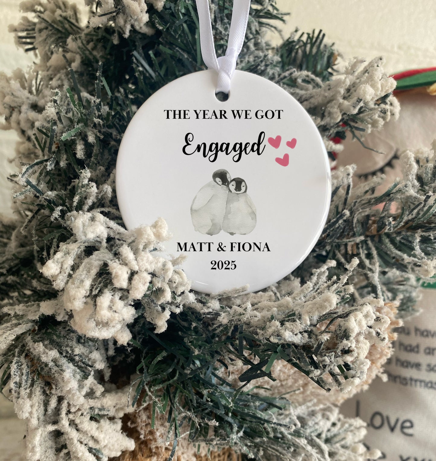 Decorative ornament with penguins and text on a Christmas tree