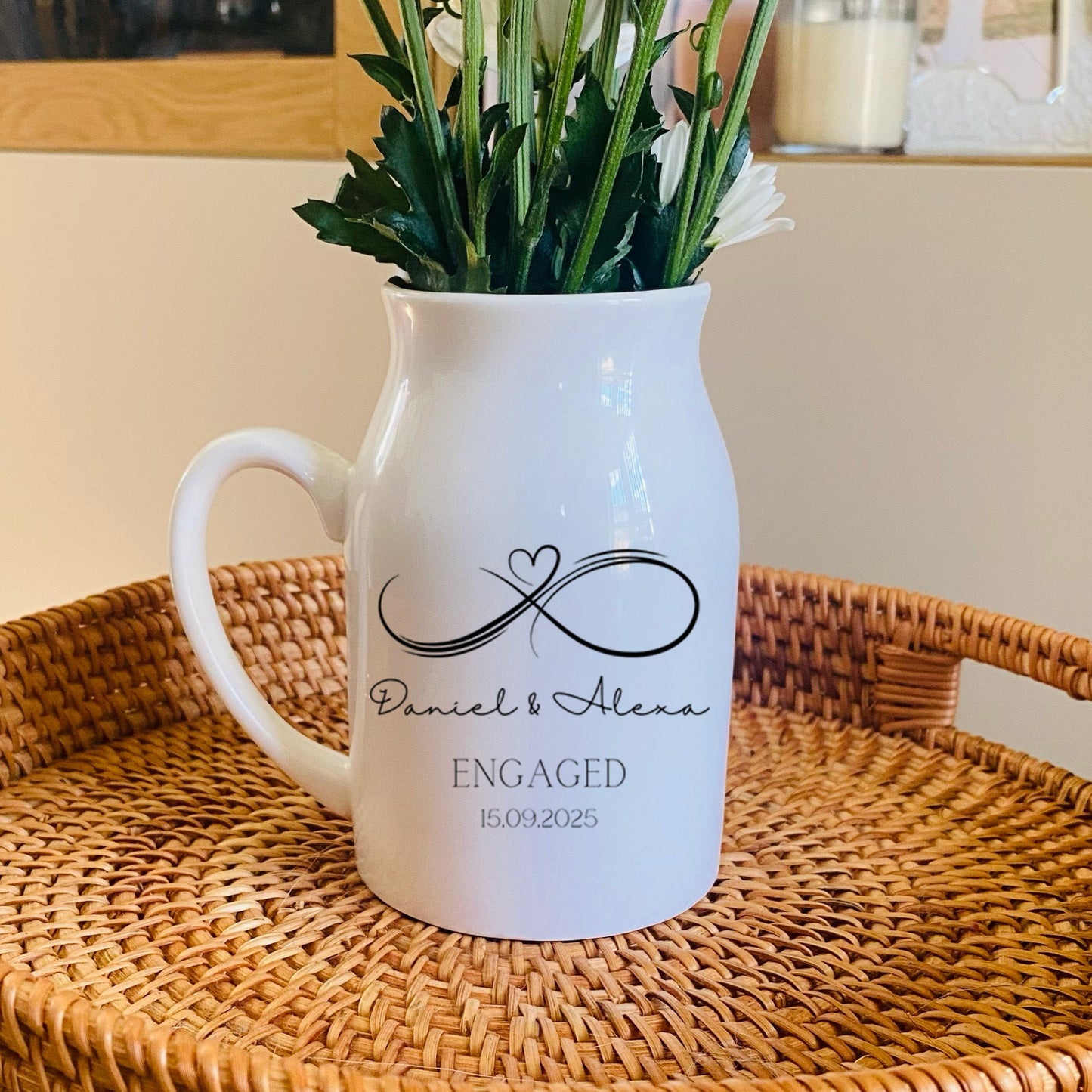 Personalised Engagement Vase, White pitcher with 'Engaged' text and an infinity sign, on a woven tray with flowers
