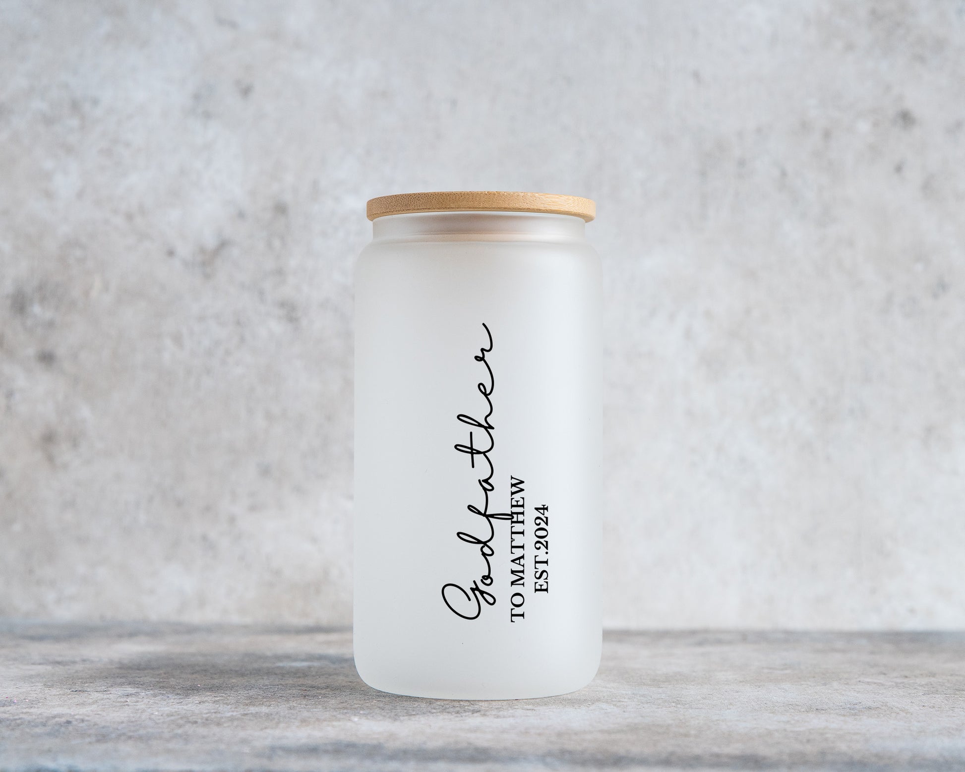 Frosted glass tumbler with a bamboo lid, featuring vertical black text that reads “Godfather to Matthew EST. 2024” – a personalized keepsake gift for a godfather announcement or christening.