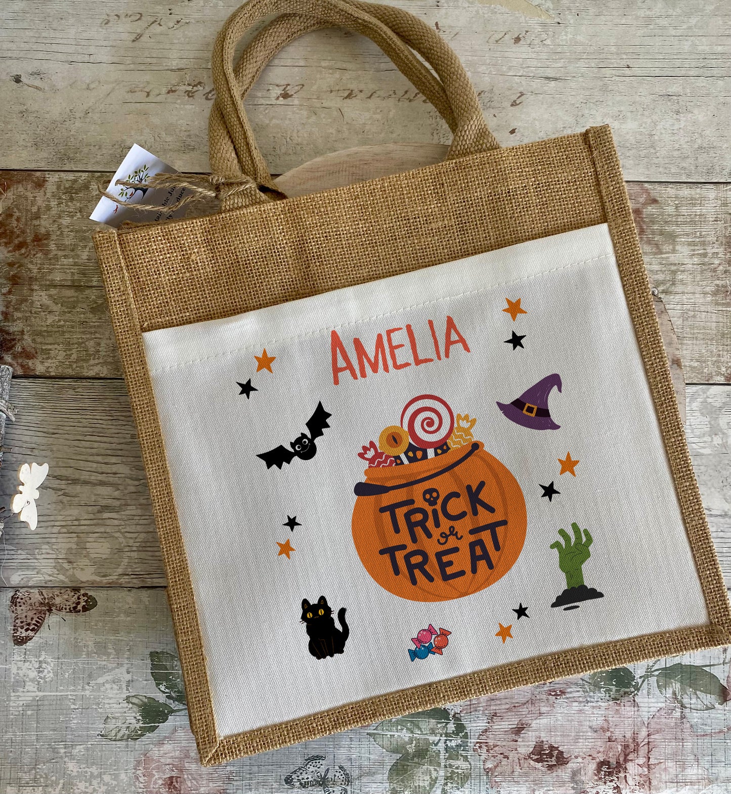Halloween-themed tote bag with 'Trick or Treat' design and name 'Amelia' on a wooden surface.