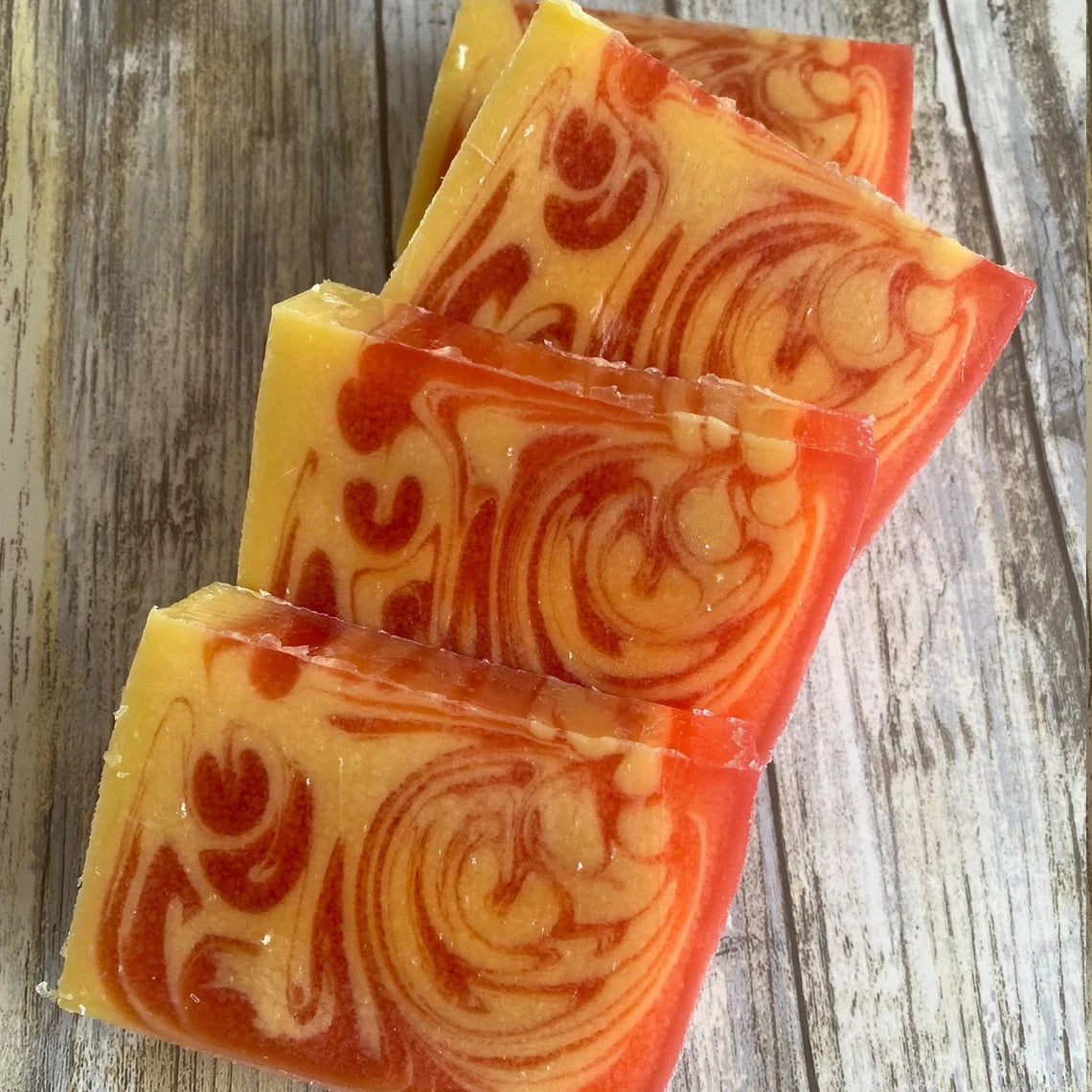 Strawberry soap with red and yellow swirl pattern on a wooden surfacer