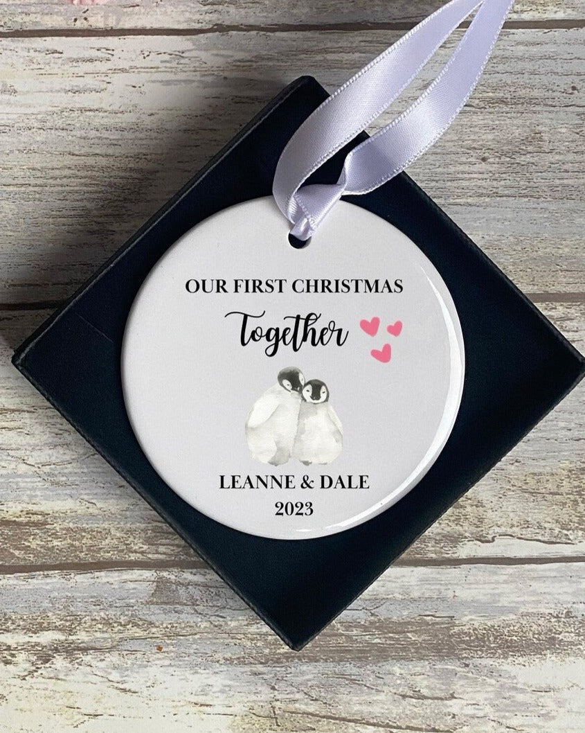 Personalised 'Our First Christmas Together' bauble with penguin couple illustration and ribbon, custom names and date – romantic ceramic ornament gift for couples, engagement or first holiday keepsake 2023