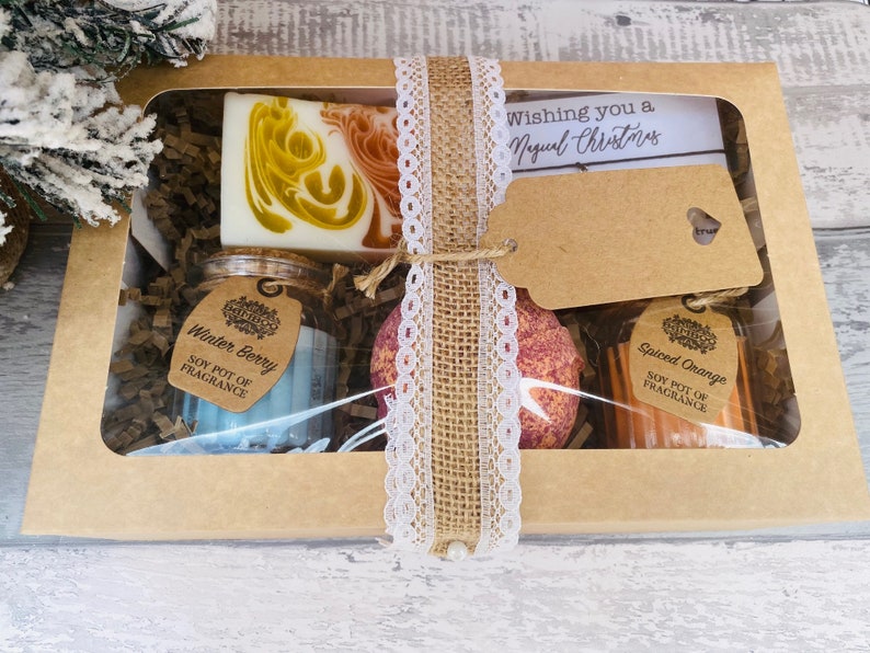 Gift set with candles and a bath bomb and soap in a box with a decorative ribbon.