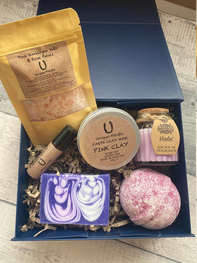 Bath and body products including a bath bomb, soap, and salts in a blue box.