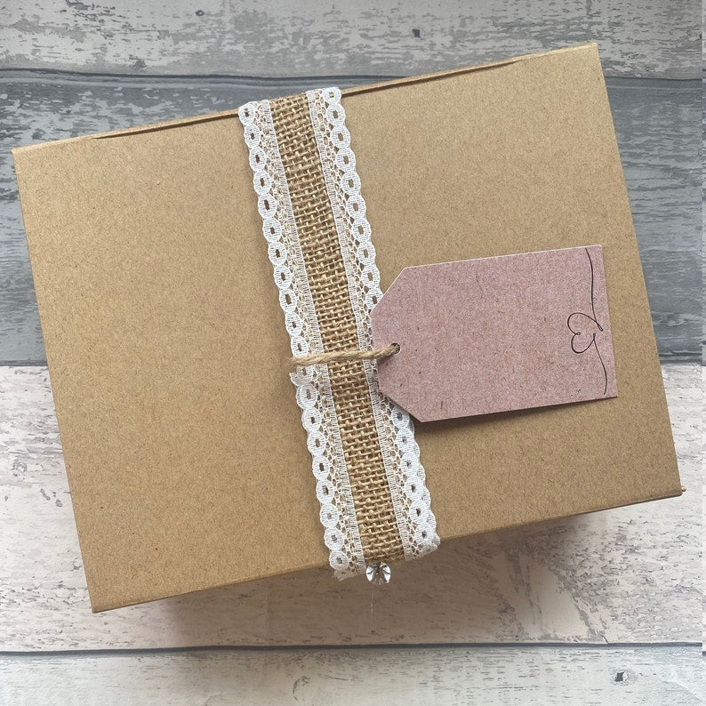 Brown paper box with lace ribbon and tag on a wooden surface