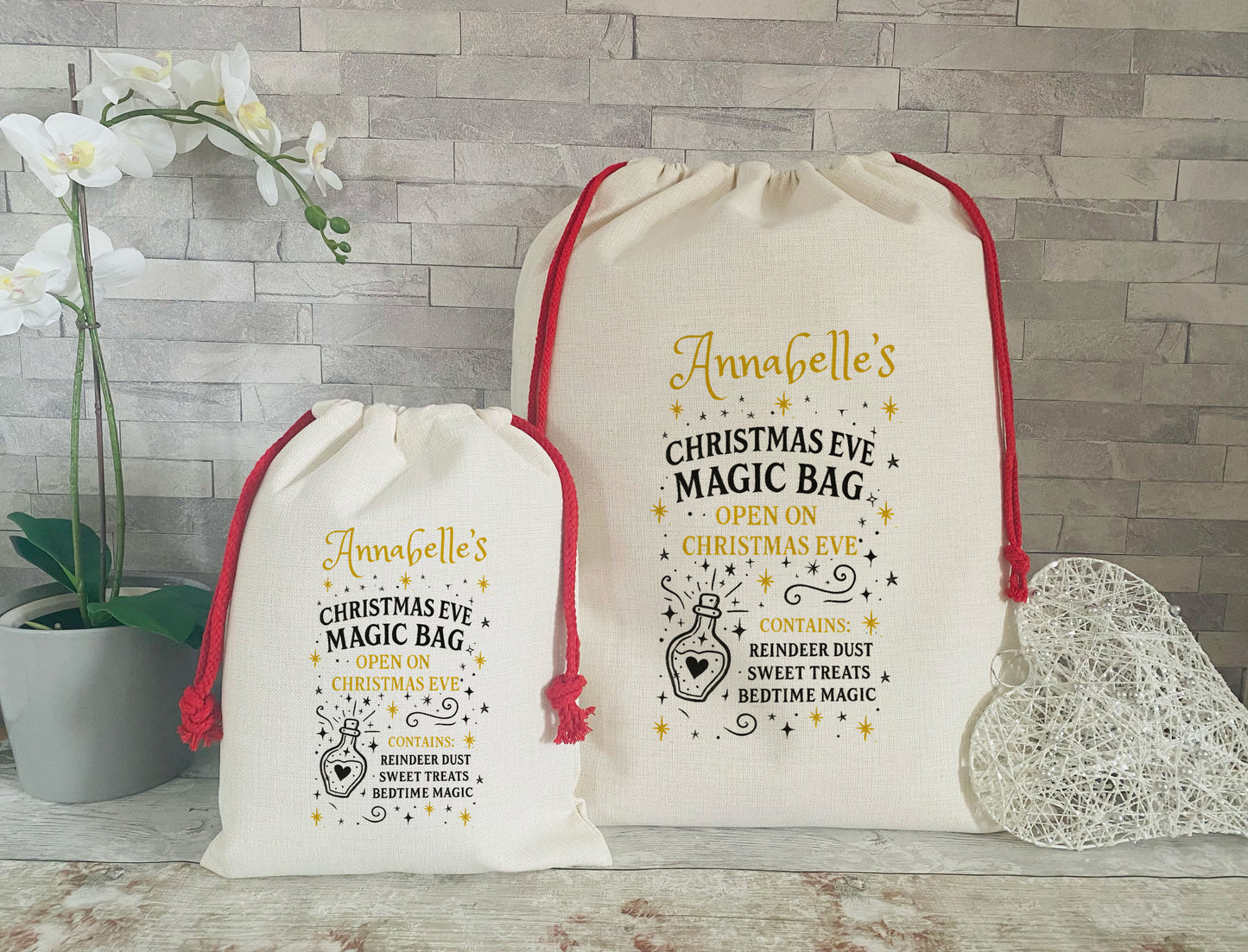 Two Christmas-themed drawstring bags with decorative text on a wooden surface.