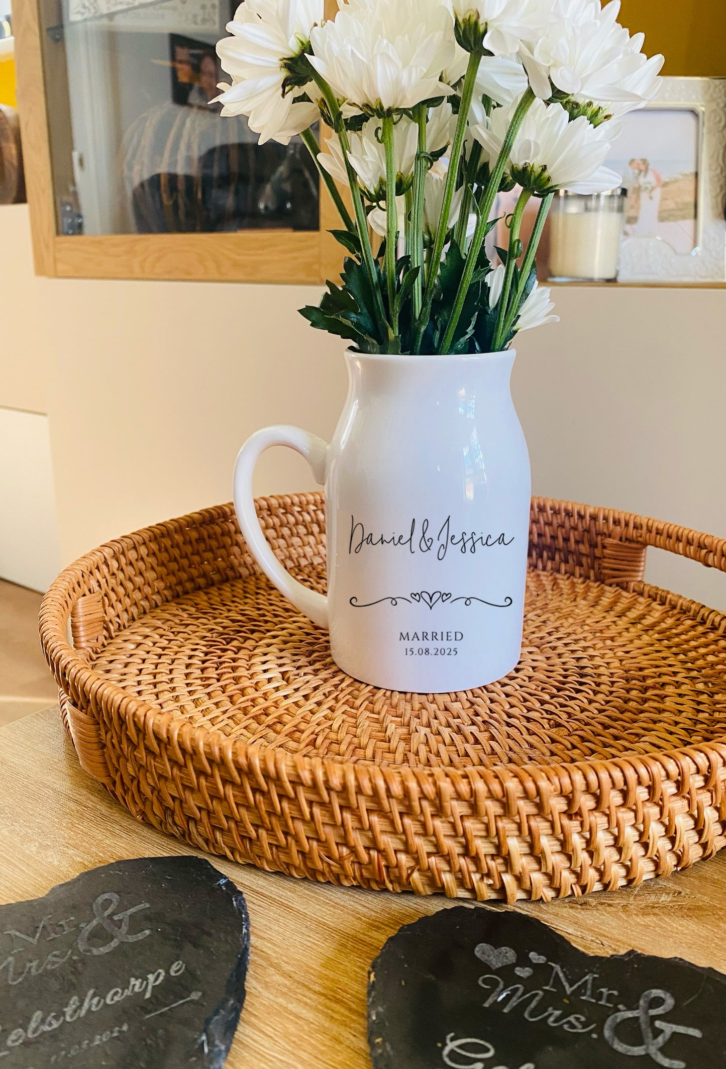 White vase with floral arrangement on a woven tray in a home setting