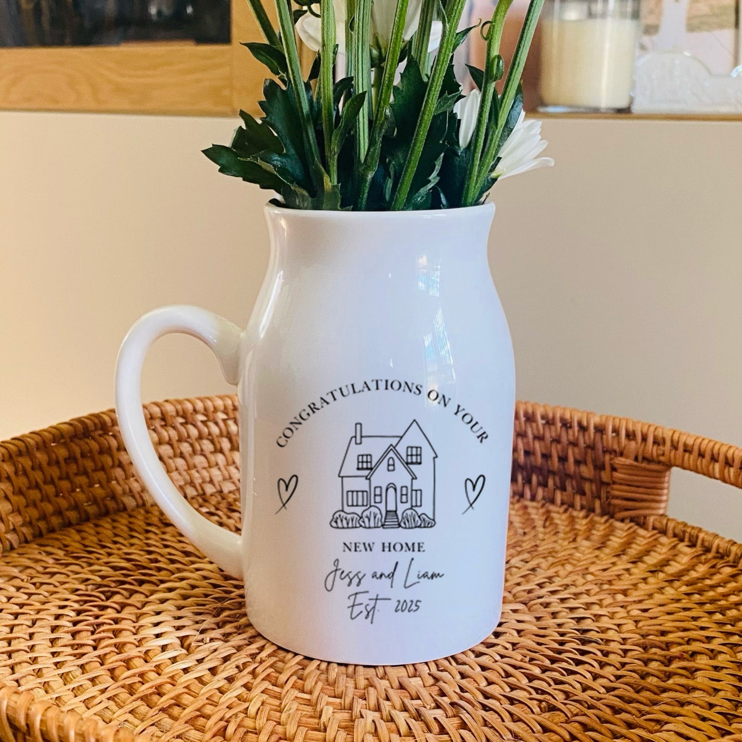 Personalised New Home Vase. A White pitcher with floral arrangement on a woven tray