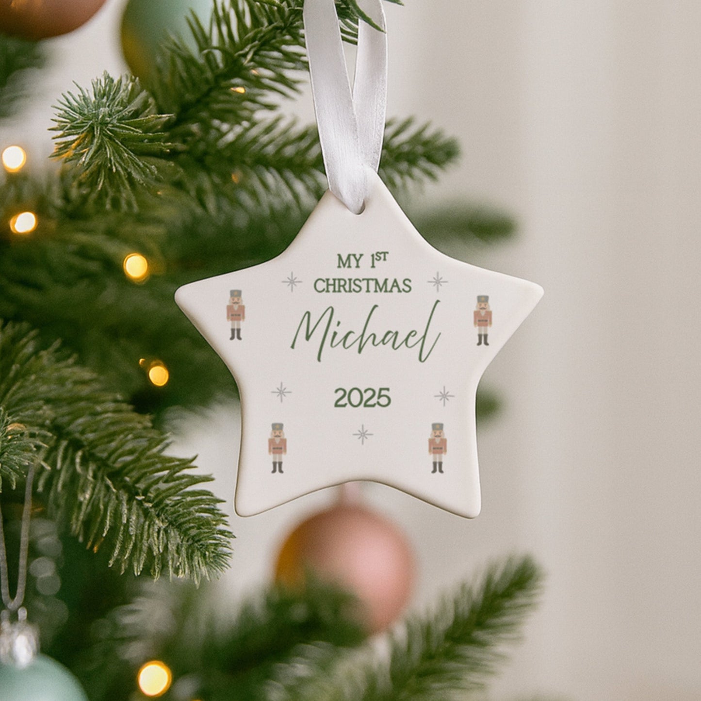 Star-shaped ornament with 'My 1st Christmas Michael 2025' text hanging on a decorated Christmas tree.