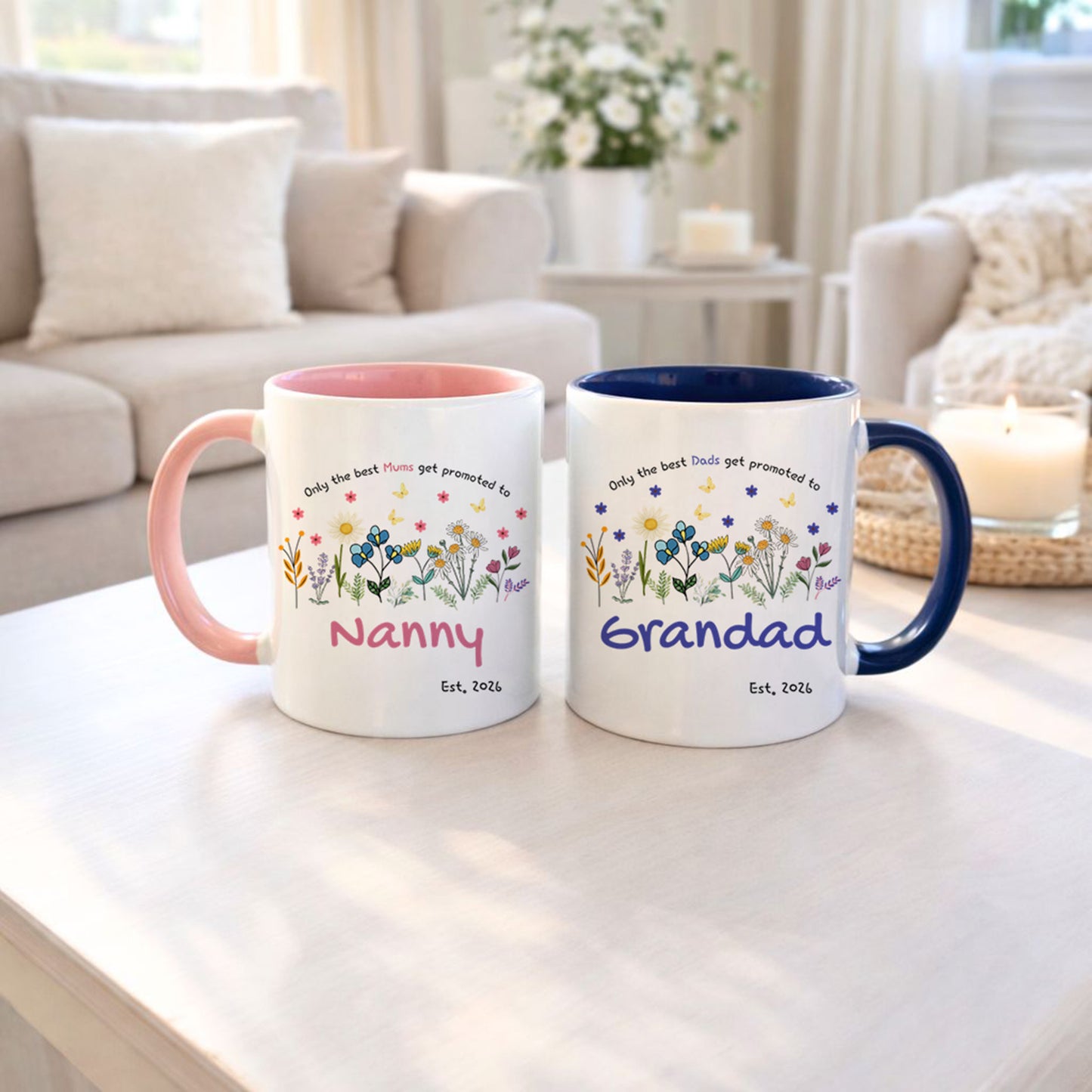 Two mugs with floral designs and text on a table in a living room setting.