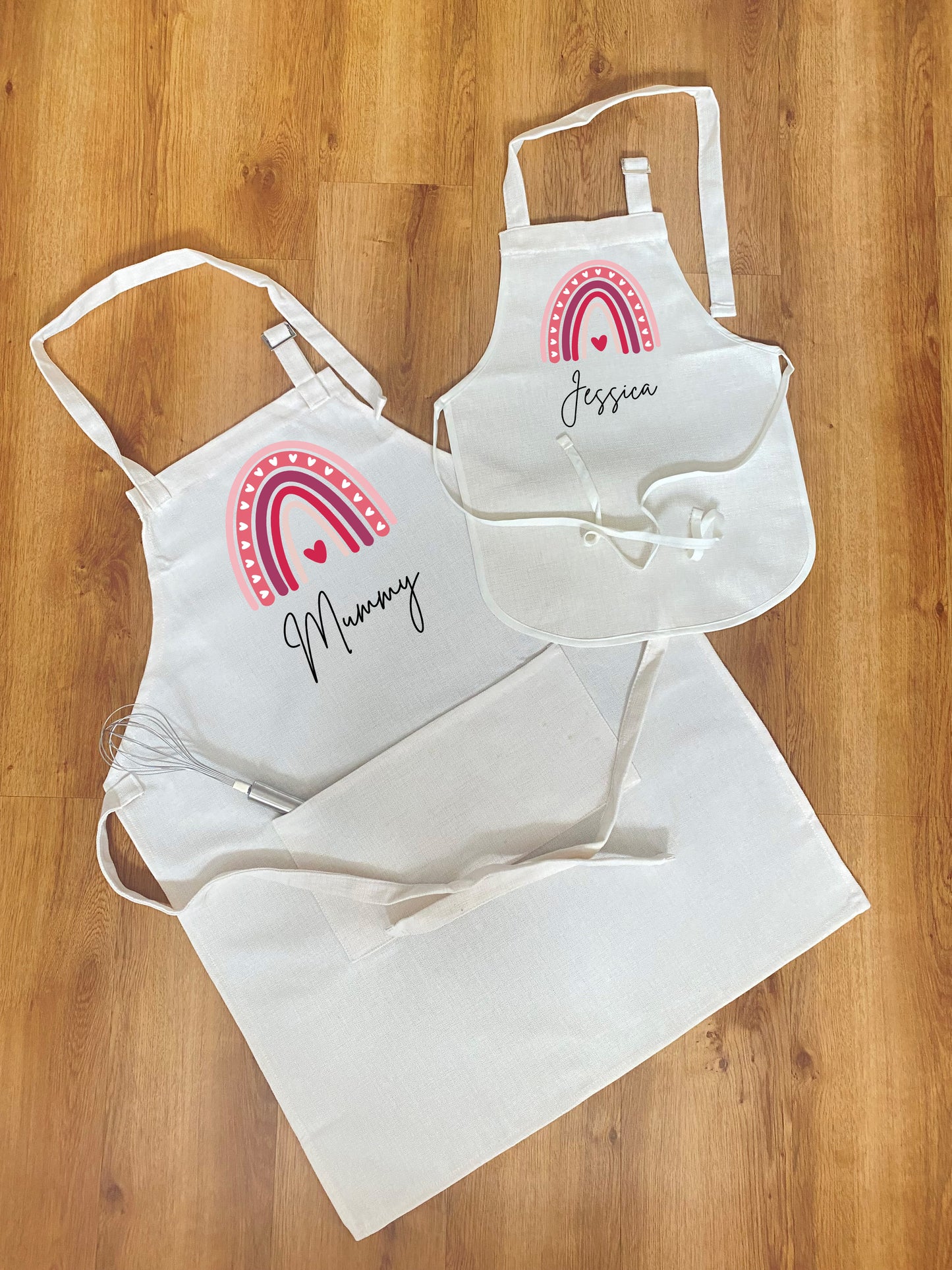 Custom mummy and daughter apron set – white aprons with cute pink heart rainbow print and personalised names, perfect Mother’s Day or birthday gift for family baking time.
